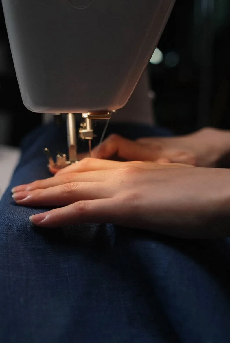 Hands guiding fabric under a sewing machine needle