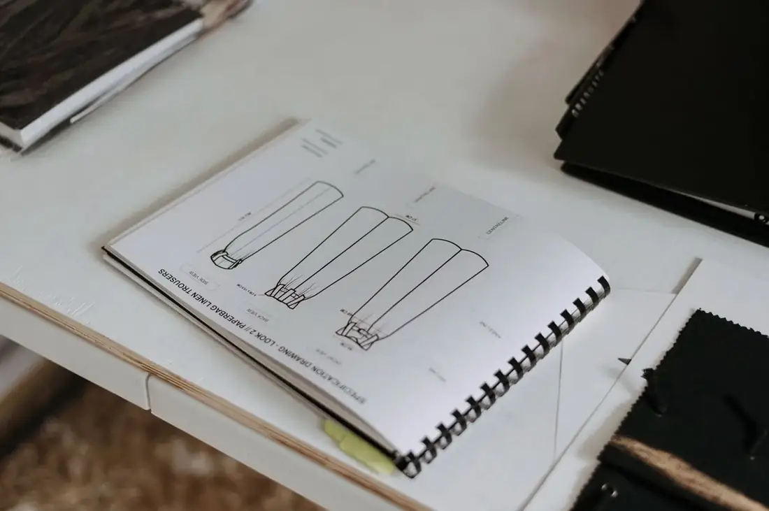 Open pattern sketchbook with garment drawings on a worktable