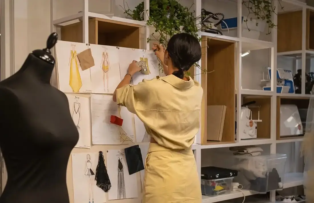 Pattern pieces pinned to a studio wall beside a dress form
